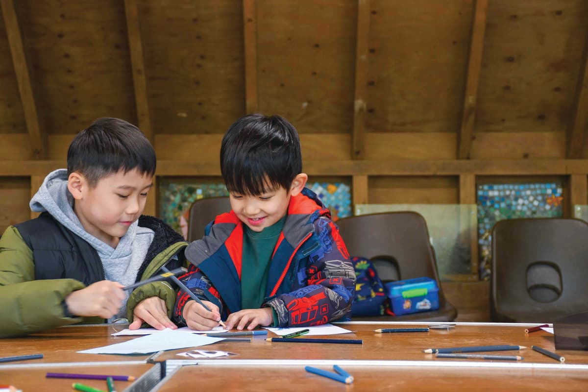 Two young boys sitting at a table working on a project