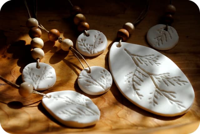 A group of ceramic necklaces sitting on top of a wooden table