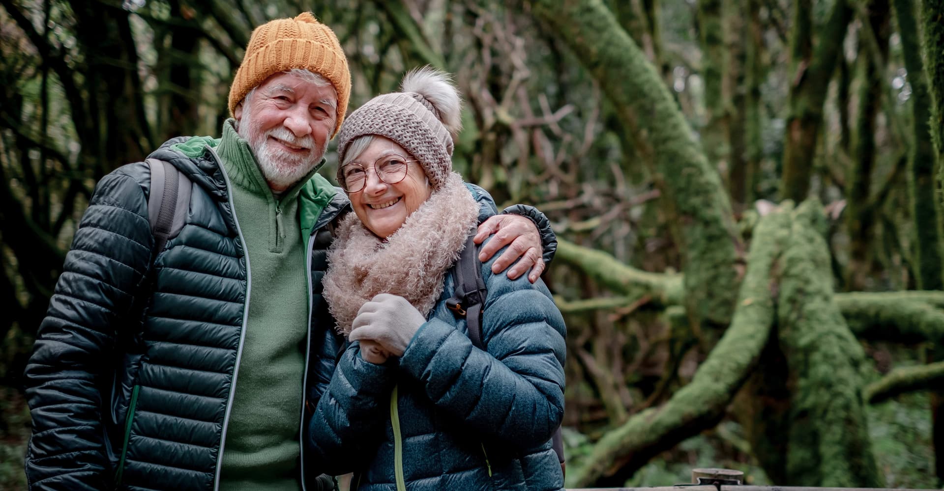 A man and woman standing next to each other in the woods