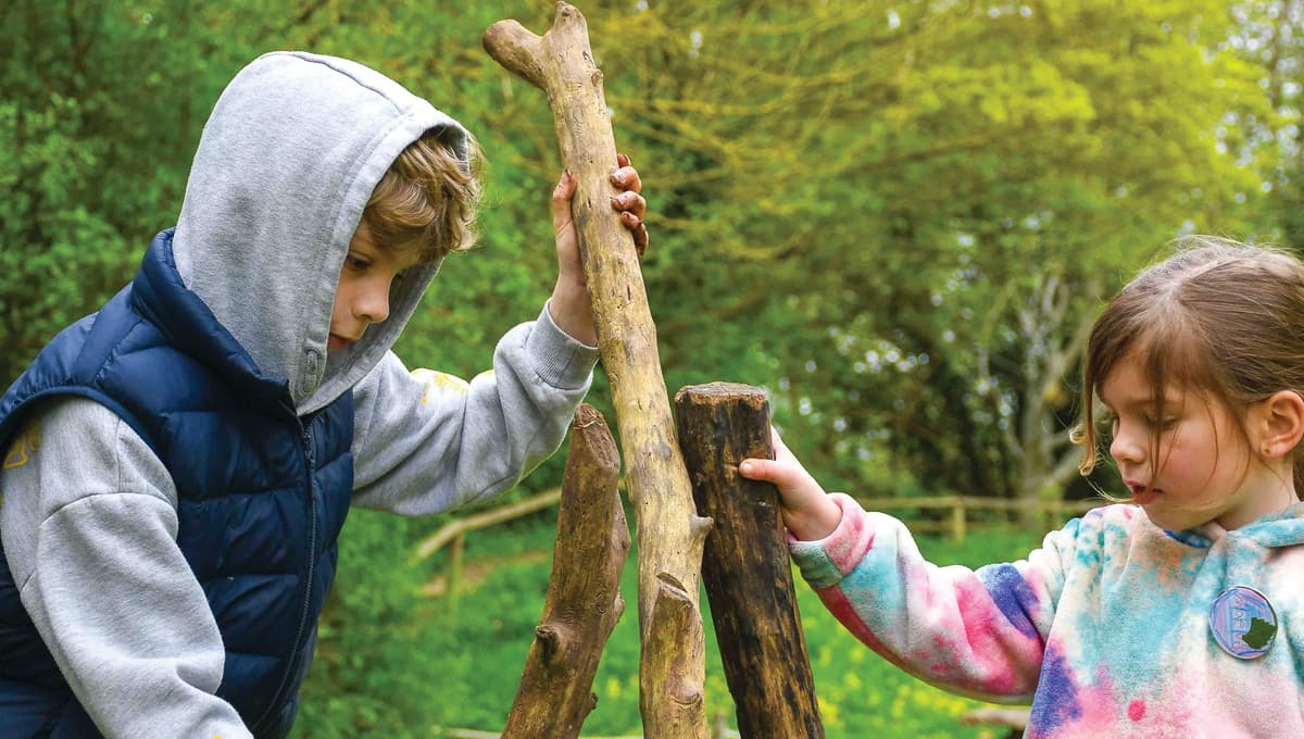 Two children are playing with a wooden structure