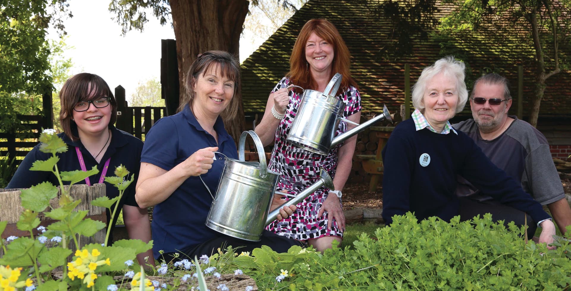 A group of people holding a metal watering can