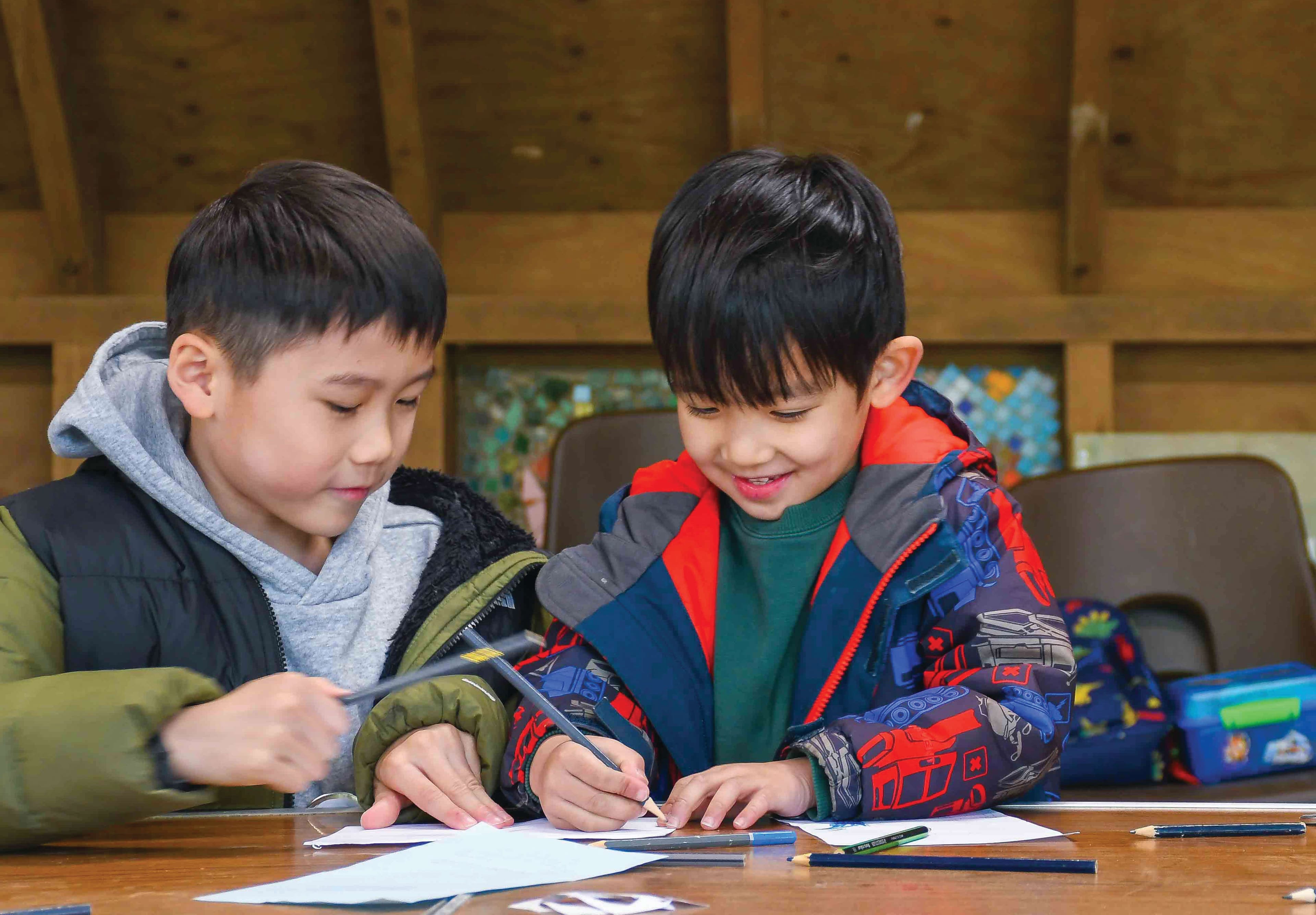 Two young boys sitting at a table working on a project