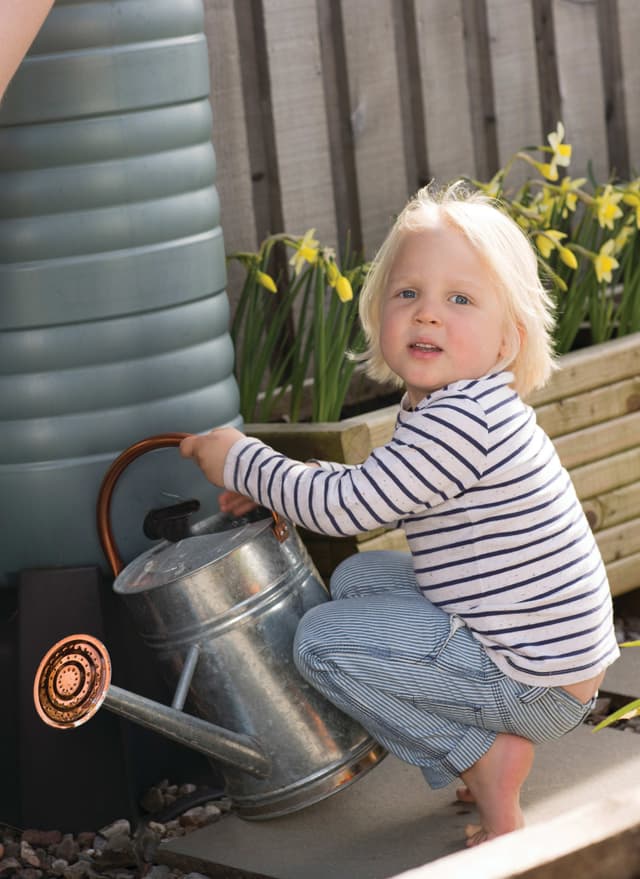A little girl is playing with a watering can