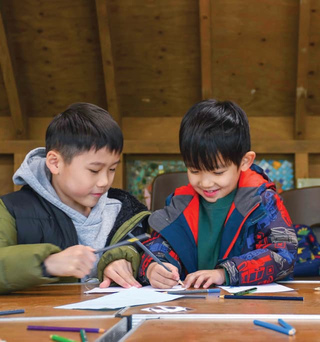 Two young boys sitting at a table working on a project