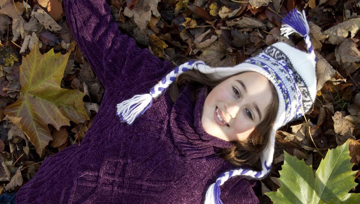 A young girl laying on the ground in leaves