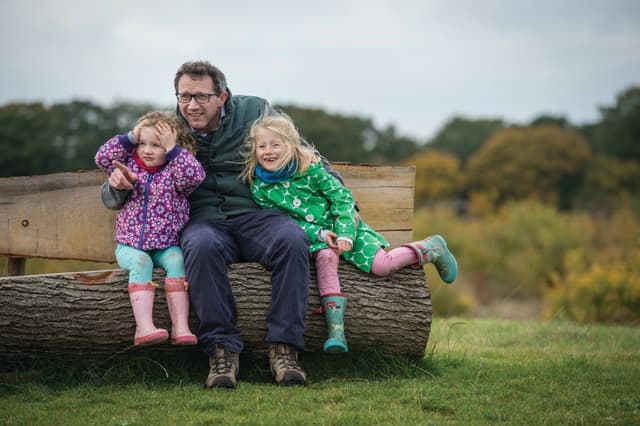 A man and two little girls sitting on a log