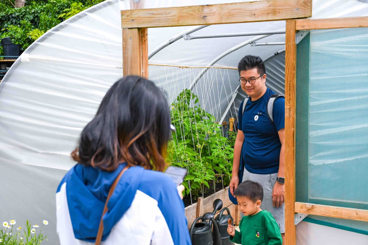 A man standing next to a little boy in a greenhouse