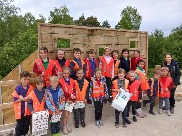 A group of children in orange vests posing for a picture